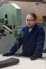 Wall Mural - Portrait of a young man in a furniture factory cutting the foam for the sofa