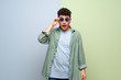 © luismolinero - Young man over blue and green background with glasses and surprised