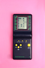 Black Tetris Game Console On Pink Background Retro And Group 80s And 90s Style With Yellow Buttons Game From Childhood