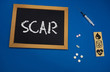 © taiga - wooden tablet on blue medical table with the word SCAR