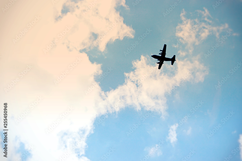wojskowy bombowiec przelatuje nad miastem na tle niebieskiego nieba - obrazy, fototapety, plakaty 