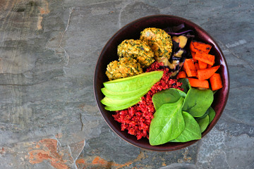 Wall Mural - Healthy vegan buddha bowl with falafels, beet quinoa, avocado, and vegetables. Top view on a dark stone background. Healthy eating concept.