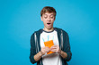 Surprised young man in casual clothes keeping mouth wide open, holding passport, boarding pass ticket isolated on blue wall background. People sincere emotions, lifestyle concept. Mock up copy space.