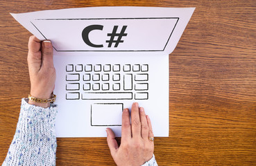  C# . woman hands and laptop drawn on paper sheet and c sharp programing language on screen