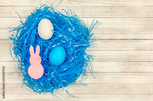 White wooden easter background with pink bunnies, white and blue easter eggs