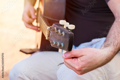 Fotomural Close up of a man's hand tuning an old acoustic guitar