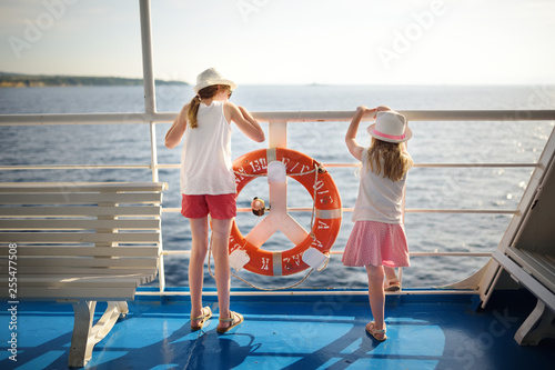 Cuadros en Lienzo Adorable young girls enjoying ferry ride staring at the sea on sunset