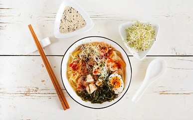 Wall Mural - Miso Ramen Asian noodles with cabbage kimchi, seaweed, egg, mushrooms and cheese tofu in bowl on white wooden table. Korean cuisine. Top view. Flat lay