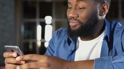 Wall Mural - Handsome african american man chatting with girlfriend in app on smartphone