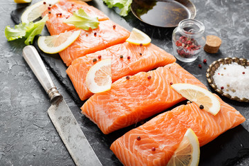 Wall Mural - Raw salmon fillet and ingredients for cooking on a dark background.