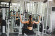 Beautiful athlete exercising with a lat pulldown machine to play the arms and shoulder muscles in the gym.