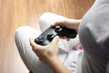 Female hands hold joystick, a young girl plays a video game