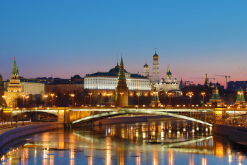  Illuminated Moscow Kremlin and Bolshoy Kamenny Bridge in the rays of rising sun. View from the Patriarshy pedestrian Bridge in Russia. Morning urban landscape in the blue hour