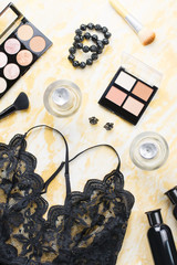 Black lace lingerie with beauty care products, make up cosmetics, jewelry in black and gold. Fashion flat lay, top view