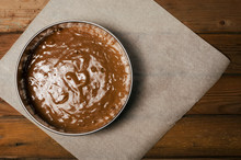 Cake Pan With Chocolate Batter And Wooden Spoon Close Up On Dark Wooden Background.
