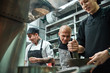 © Friends Stock - I'm watching you Strict chef in apron looking carefully how his assistant working at restaurant kitchen
