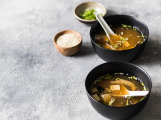 Wall Mural - Japanese miso soup with oyster mushrooms in a black bowls with a spoon on a grey background