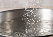 Add salt to boiling water in a metal pan close-up
