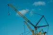 Yellow cranes at construction site with blue sky