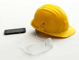 Yellow helmet, protective glasses and mobile phone.