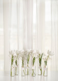 Fototapeta Kuchnia - White tulips in bottles with Easter decoration in the form of eggs on a white table.