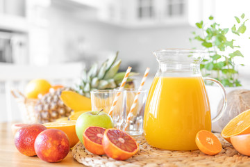 Wall Mural - Multifruit juice and fresh fruit on table on kitchen background closeup