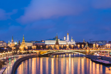  Illuminated Moscow Kremlin and Bolshoy Kamenny Bridge in the rays of setting sun. View from the Patriarshy pedestrian Bridge in Russia. Evening urban landscape in the blue hour