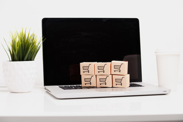 Online shopping . ecommerce and delivery service concept : Paper cartons with a cart or trolley logo on a laptop keyboard, depicts customers order things from retailer sites via the internet