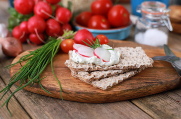 Wall Mural - crispbread with quark and fresh chive, radish and tomatoes on a rustic wooden table - healthy breakfast with fresh herbs 