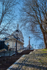 Wall Mural - Typical Montmartre staircase with old street lamp and sacre coeur in background in winter - Paris, France