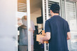 © wutzkoh - Asian man accepting delivery from a male courier at in front of home.