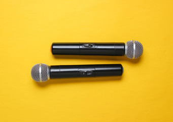 Two wireless microphone on yellow background. Flat lay.  Top view