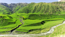 The Village Is On A Mountain Plateau. Mountain Slopes Are Covered With Bright Green Vegetation