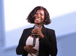 © TheVisualsYouNeed - confident black afro American business woman with microphone speaking in auditorium at corporate event or seminar giving motivation and success coaching