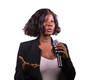 © TheVisualsYouNeed - beautiful black afro American business woman with microphone speaking in auditorium at corporate event or seminar giving motivational coaching speech isolated