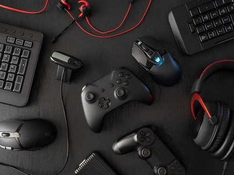 gamer workspace concept, top view a gaming gear, mouse, keyboard, joystick, headset, mobile joystick, in ear headphone and mouse pad on black table background with copy space.
