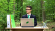 © motortion - Businessman working on laptop in park making breakthrough in nature conservation