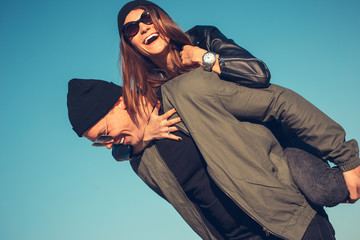 Young couple in love walks by the sea. Spring, autumn. The guy is wearing a jacket and hat. Girl in a hat and leather jacket with a scarf and glasses