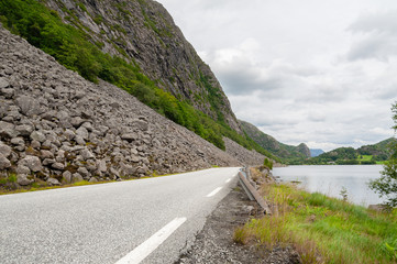 Open road running along water line of a lake. Empty road with no traffic in countryside. Rural landscape. Ryfylke scenic route. Norway.