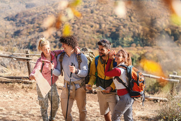 Poster - Four happy hikers standing on the glade and enjoying nature in autumn.