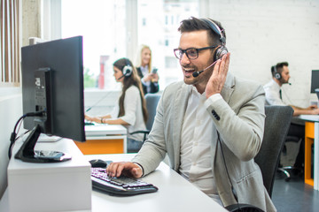 Wall Mural - Friendly customer support agent with headset working in call center.