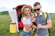 © pantovich - Young couple preparing things for travel standing in nature near the car
