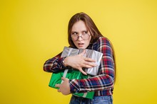 Beautiful Girl In Plaid Shirt Greedily Holding Gift Boxes In Isolated Room On Yellow Background