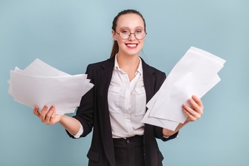 Young girl office worker in glasses in classic costume holding documents isolated in the room on a blue background