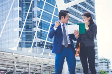 Wall Mural - Asian businessman and businesswoman holding document and rising up hand. concept of business success.