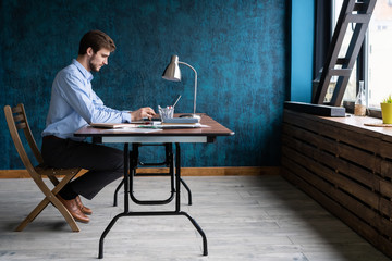 Wall Mural - Happy young businessman using laptop at his office desk.