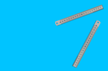 Pair of metal straightedges with digits and scale on blue background with copy space for your text