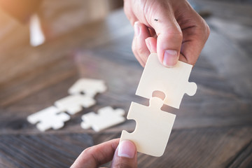 hand holding piece of jigsaw at modern office Business partnership concept