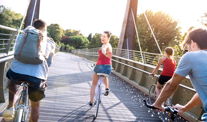 happy friends millennial having fun riding bike at city park - friendship concept with young milleni