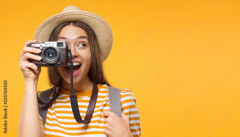 Tourism concept. Horizontal banner of excited young woman tourist holding photo camera, isolated on yellow background with copy space - obrazy, fototapety, plakaty 